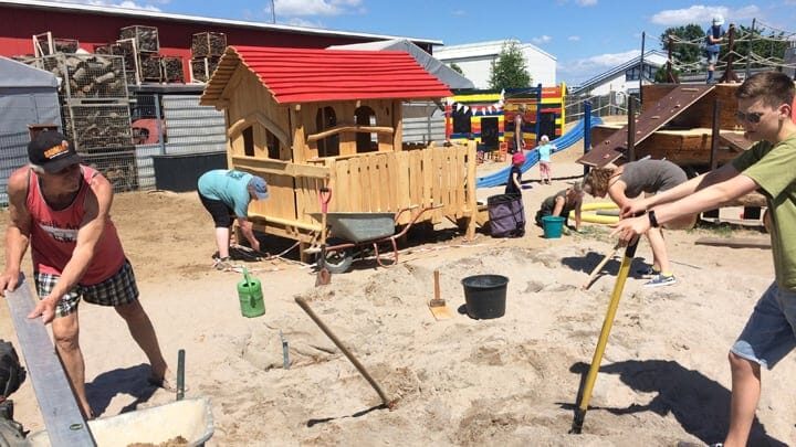 Eine Gruppe Kinder baut einen Sandkasten im Sand.