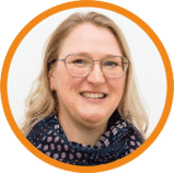 christusgemeinde-ga- Eine Frau mit blonden Haaren, Brille und einem gemusterten Schal lächelt in die Kamera. Das Bild wird von einem orangefarbenen Kreis auf weißem Hintergrund eingerahmt.